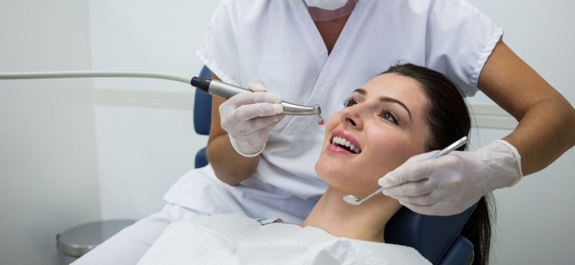 Dentist examining a female patient with tools at dental clinic